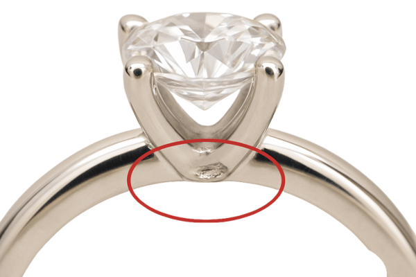 Sužadėtuvių žiedas iš balto aukso su gamybos defektu – akmens įtvirtinimo netolygumas ir metalo paviršiaus nelygumai, atsiradę dėl gamybos klaidų ar medžiagų trūkumų