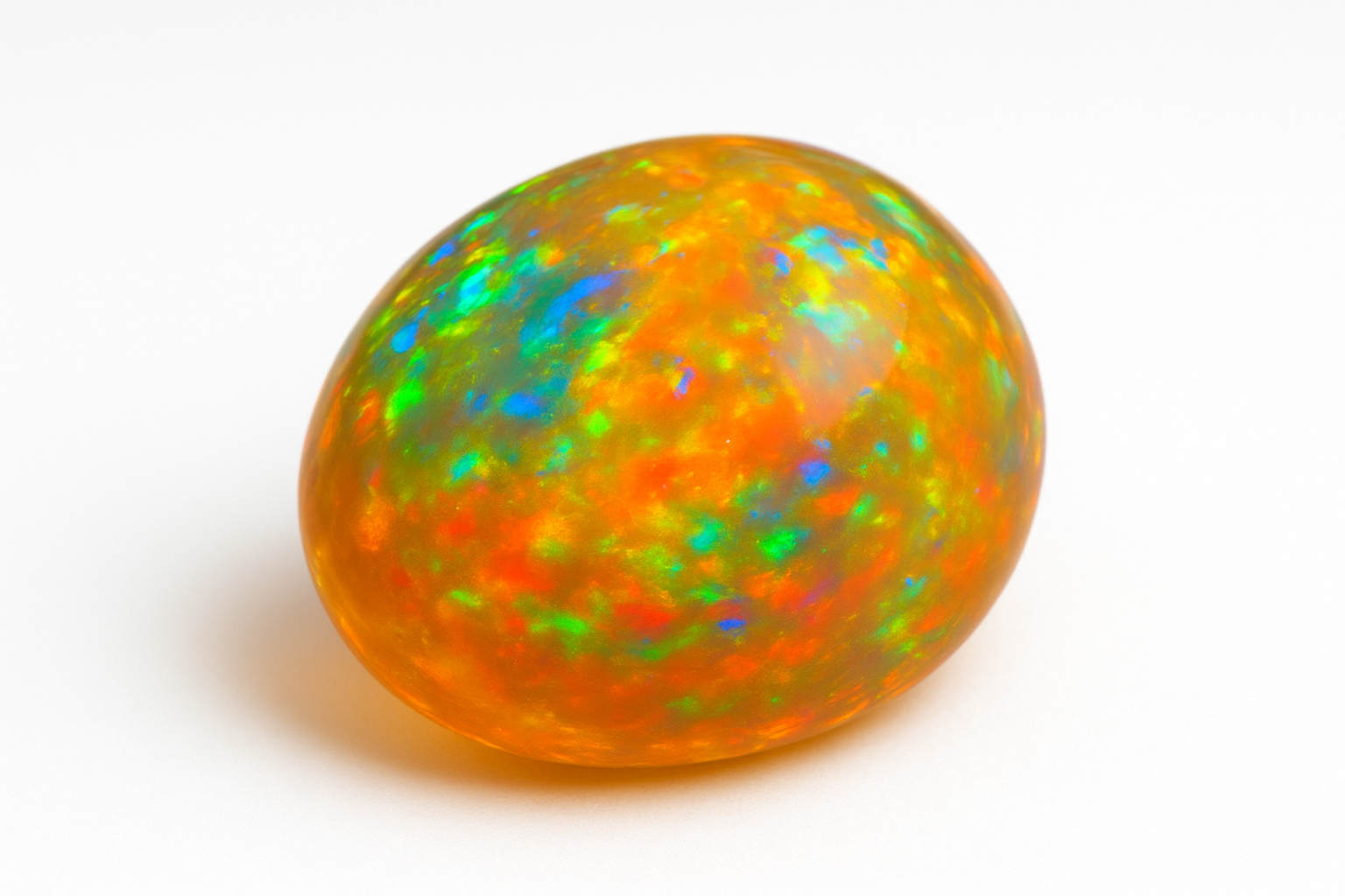 Ebatavalise kujuga kollane opaal kuldse alatooni ning eredate roheliste, siniste ja punaste sähvatustega, valgel taustal