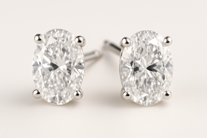 Auskarai su deimantais, įstatytais į elegantišką keturių kojelių tvirtinimą, neutraliai šviesiame fone