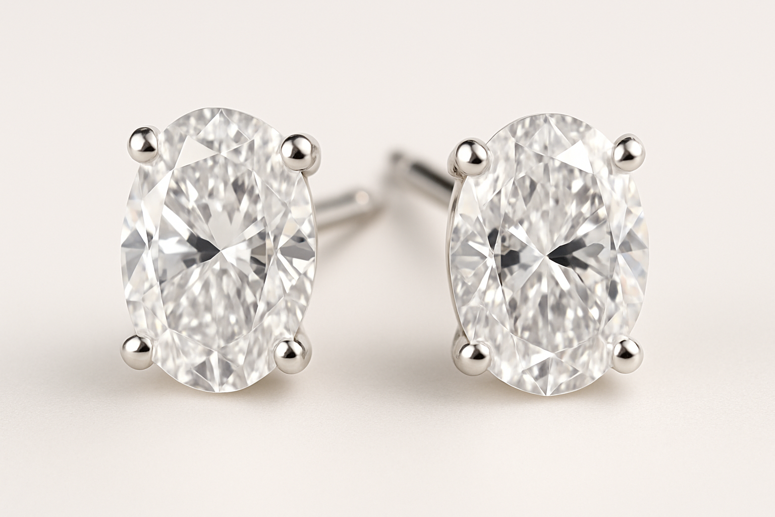 Auskarai su ovalo formos deimantais, įstatytais į elegantišką keturių kojelių tvirtinimą, neutraliai šviesiame fone