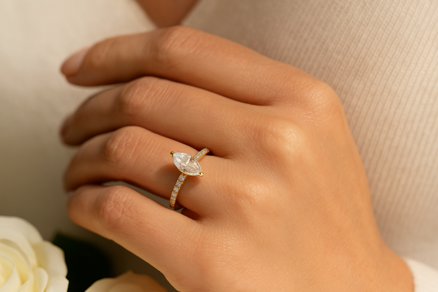 Stilingos moters ranka su moderniu sužadėtuvių žiedu iš geltono aukso, kuriame centre marquise formos deimantas, o lankelis puoštas smulkiais deimantais