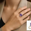 Stilingos moters ranka su auksiniu žiedu, puoštame trikampio formos violetiniu topazu ir deimantais